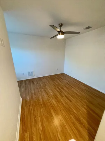 an empty room with wooden floor and fan