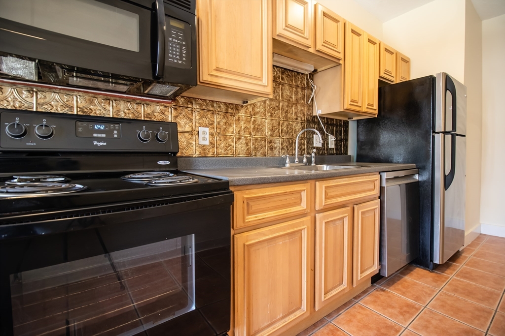 12 Ransom Road, Unit 6 Boston, MA 02135 - Photo 2 of 16 a kitchen with stainless steel appliances granite countertop a stove microwave and refrigerator