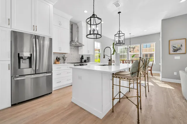 a kitchen with stainless steel appliances granite countertop a refrigerator a sink dishwasher a stove and white cabinets with wooden floor