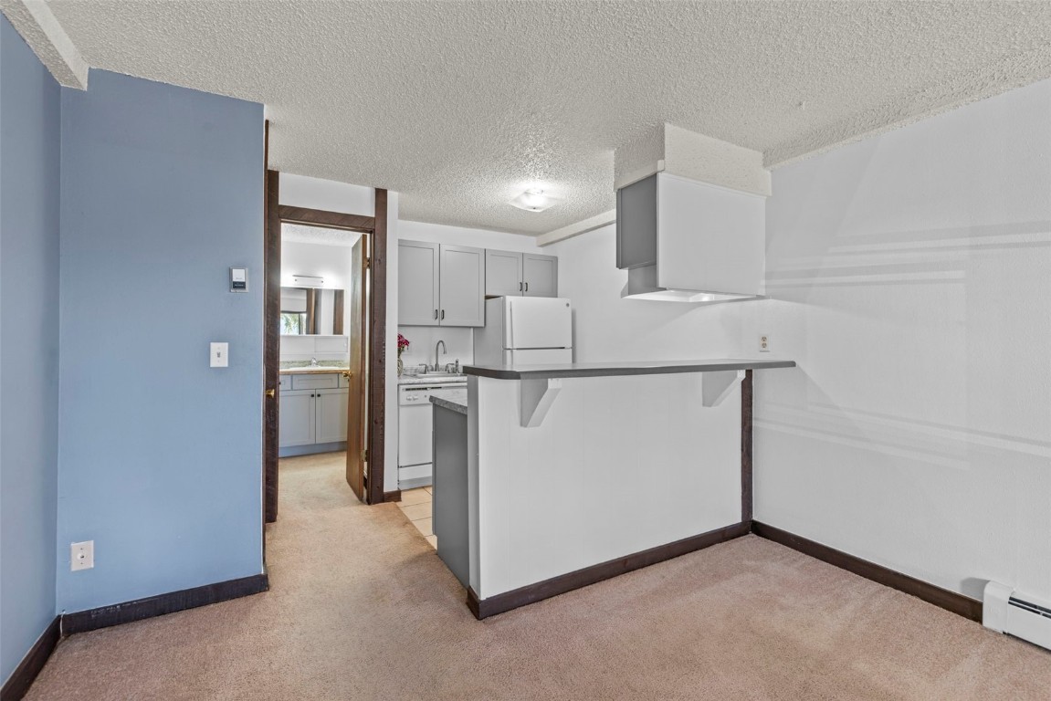 7307 Ryan Gulch Road, Unit 7307 Silverthorne, CO 80498 - Photo 5 of 20 a view of a kitchen with refrigerator and white cabinets