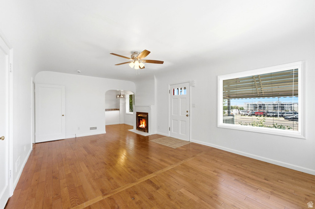 1925 South Main Street Bountiful, UT 84010 - Photo 9 of 48 Living area featuring wood-finish flooring, a ceiling fan, a fireplace with a white mantel, and a front entry door with glass inserts