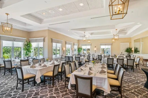 a room with lots of tables a large window and chairs