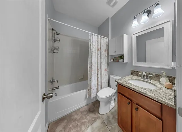 a bathroom with a granite countertop sink toilet mirror and a bathtub