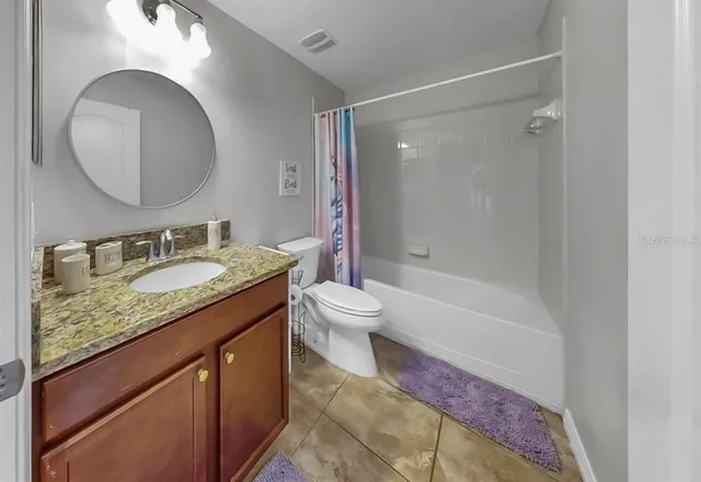 a bathroom with a granite countertop sink toilet mirror and bathtub