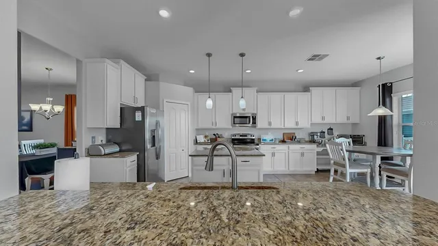 a kitchen with stainless steel appliances kitchen island granite countertop a refrigerator and microwave