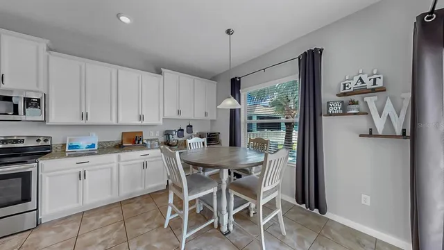 a kitchen with stainless steel appliances granite countertop a stove top oven a sink dishwasher and white cabinets with wooden floor