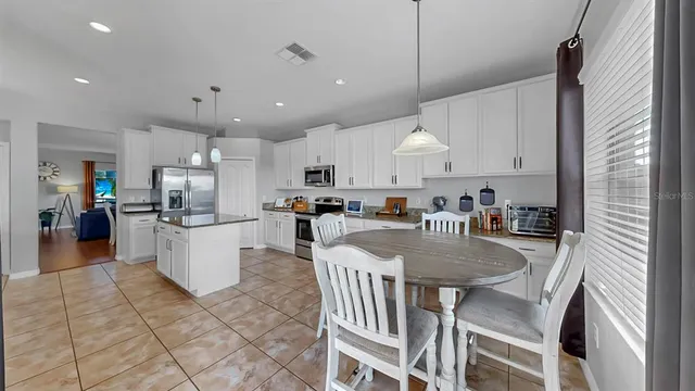 a kitchen with stainless steel appliances granite countertop a stove top oven a sink a dining table and chairs