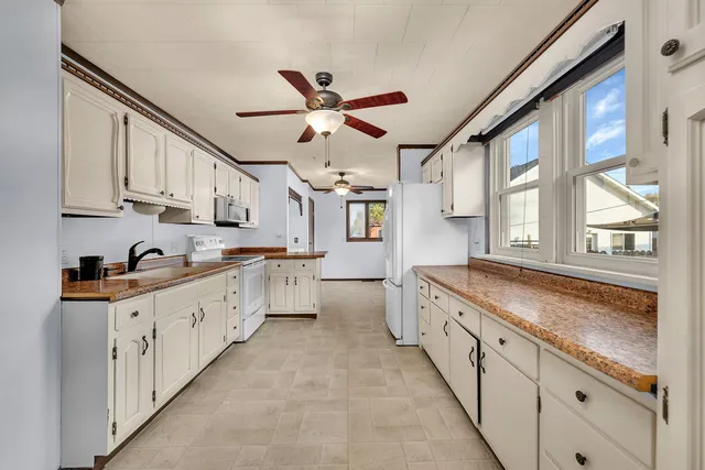 a large kitchen with granite countertop a large window and white stainless steel appliances
