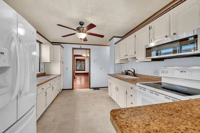 a large kitchen with stainless steel appliances granite countertop a stove a sink and white cabinets