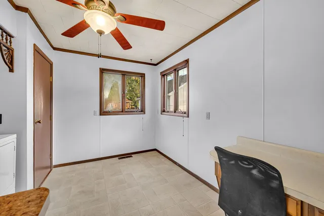 a view of an empty room with window and a chandelier fan