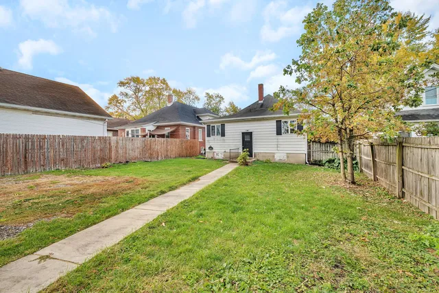 a view of a house with a big yard and large tree