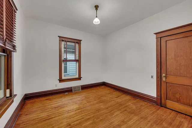 a view of an empty room with window and wooden floor