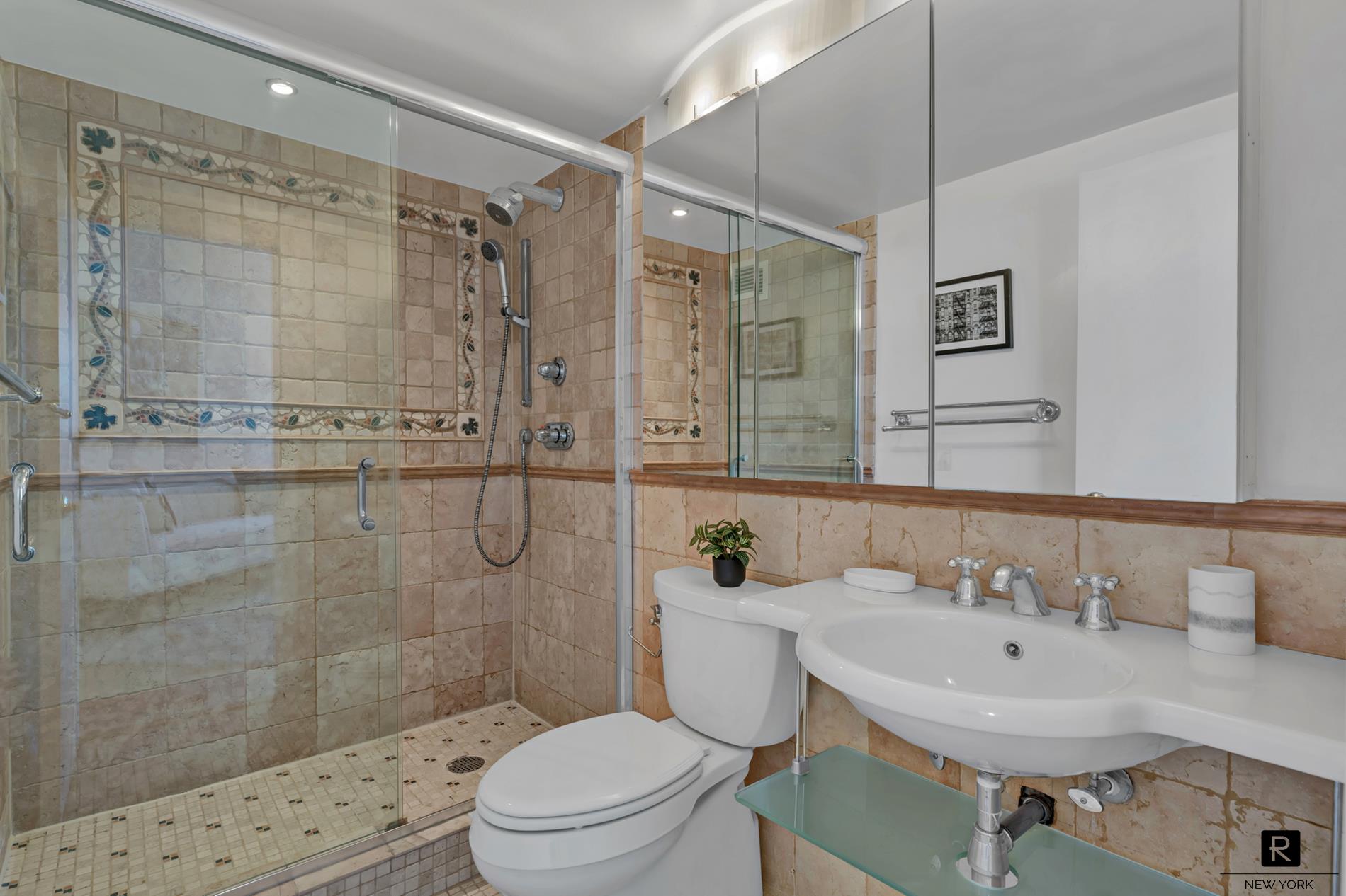 415 East 37th Street, Unit 27D Manhattan, NY 10016 - Photo 5 of 17 a bathroom with a sink toilet a mirror and shower