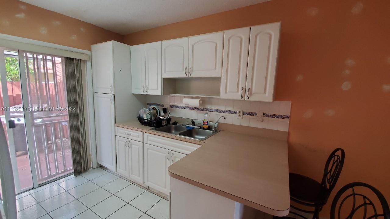 5830 West 18th Lane, Unit 101 Hialeah, FL 33012 - Photo 6 of 14 a kitchen with a sink a stove and cabinets