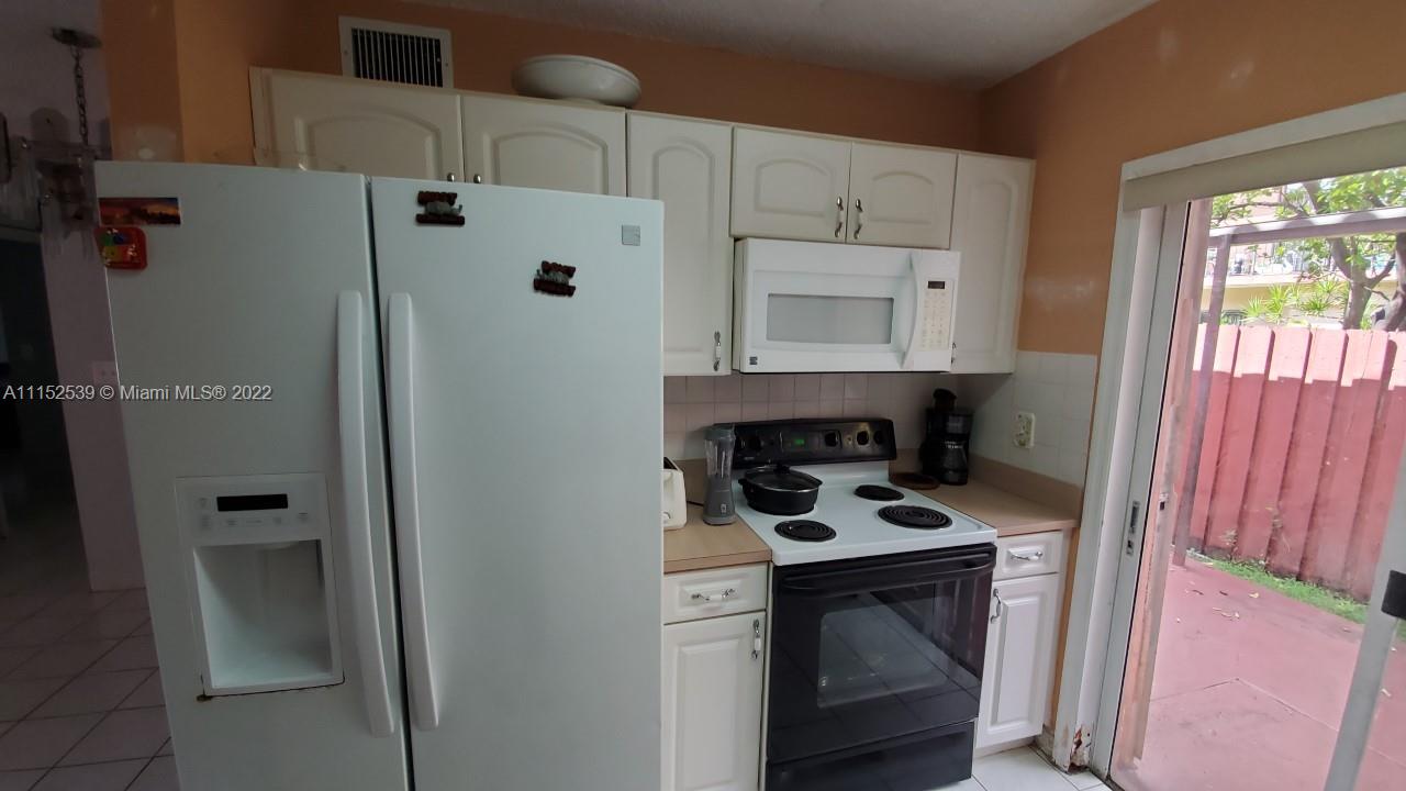 5830 West 18th Lane, Unit 101 Hialeah, FL 33012 - Photo 7 of 14 a kitchen with white cabinets and white appliances