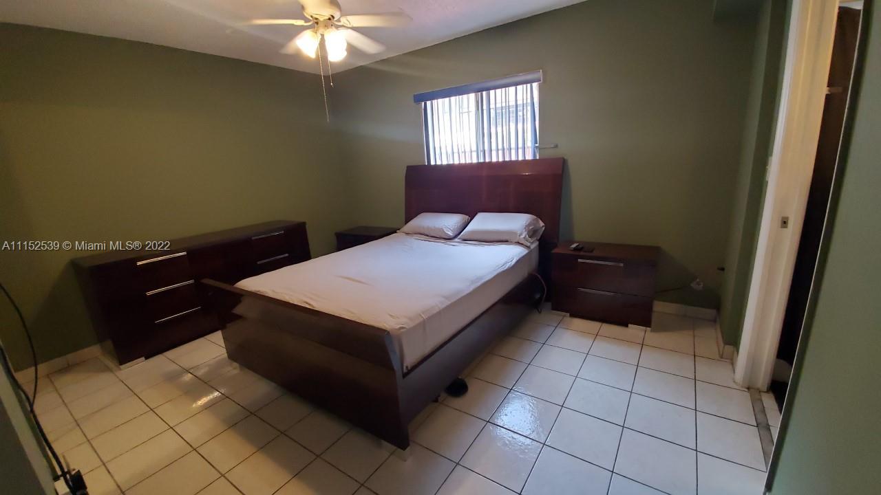5830 West 18th Lane, Unit 101 Hialeah, FL 33012 - Photo 8 of 14 a bedroom with a bed and a chandelier