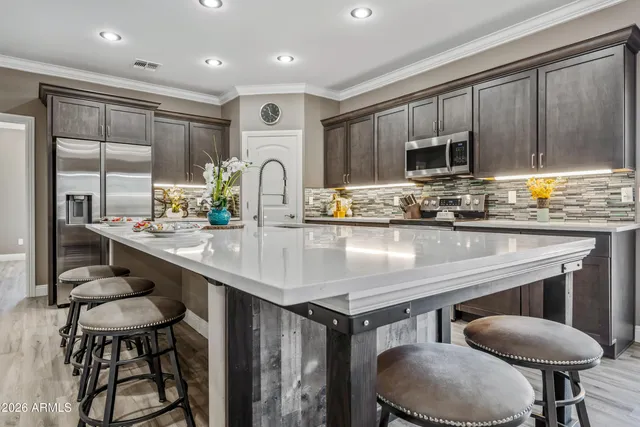 a kitchen with kitchen island granite countertop a refrigerator and a sink