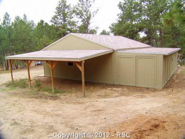 6980 Baker Road Colorado Springs, CO 80908 - Photo 9 of 25 Back of Building with Covered Awning and Access Doors to Stall Area with Dirt Floor