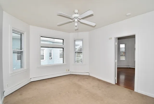 an empty room with windows and ceiling fan