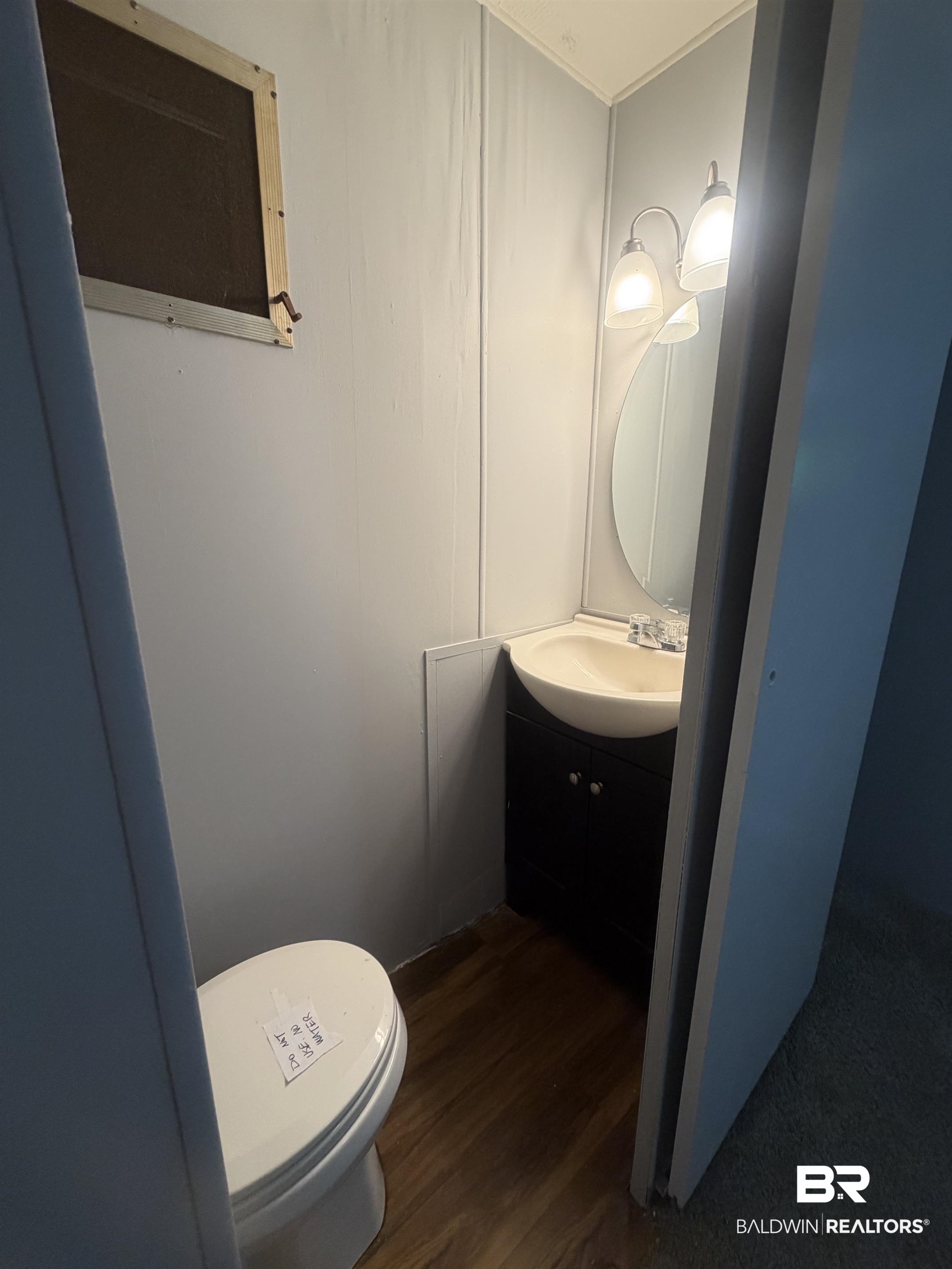 1354 Caney Loop Lillian, AL 36549 - Photo 14 of 45 Compact bathroom featuring a white toilet, wood-finish flooring, and a corner vanity with a built-in sink