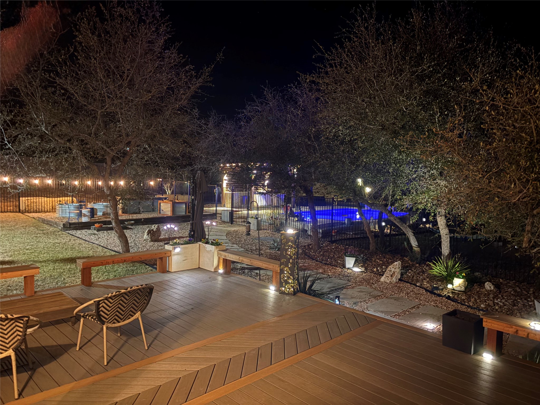Deck at night featuring a fenced backyard