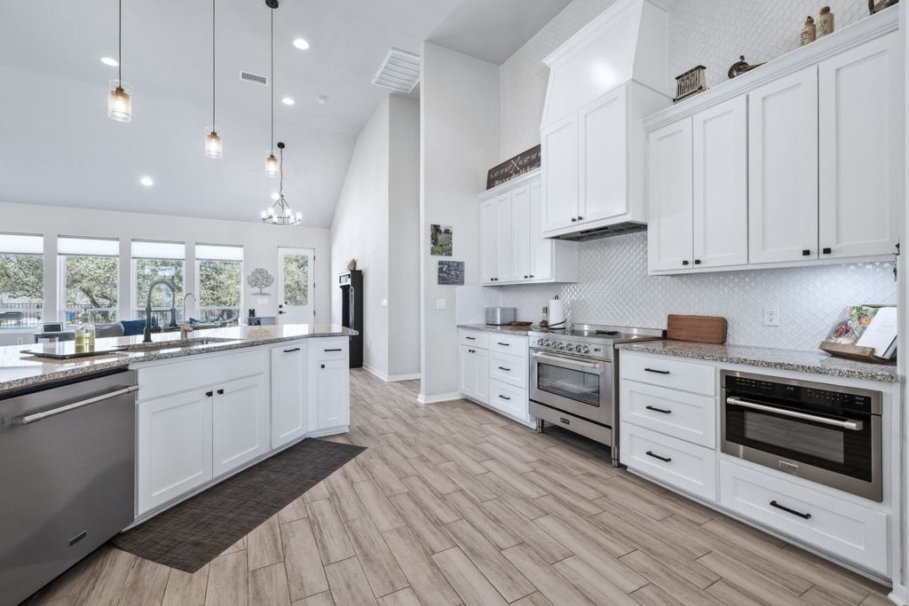 14302 Summit View Drive, Unit 4 Leander, TX 78641 - Photo 9 of 40 Kitchen featuring white cabinetry, stainless steel appliances, light stone countertops, decorative backsplash, and lofted ceiling