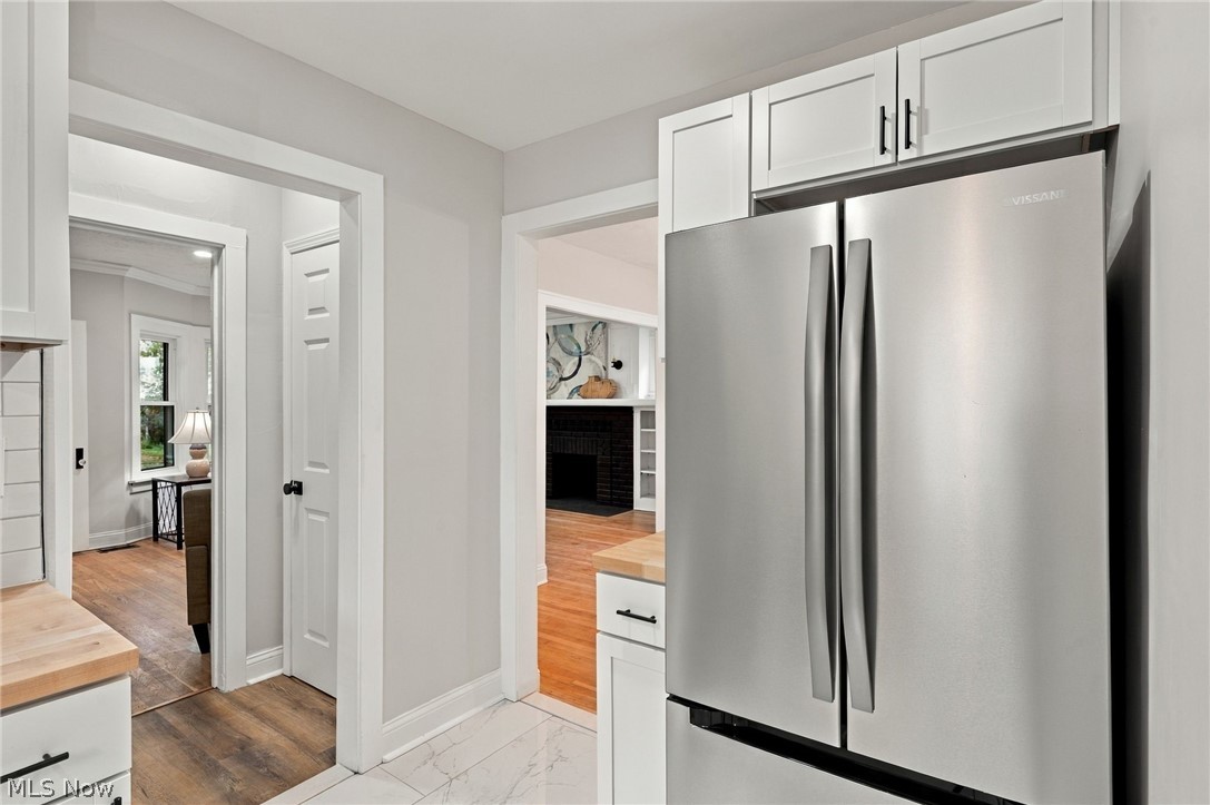 1173 Yellowstone Road Cleveland Heights, OH 44121 - Photo 16 of 44 Stainless steel refrigerator with a French door design, white shaker cabinetry with black pulls, light wood-finish countertops, and white tile flooring