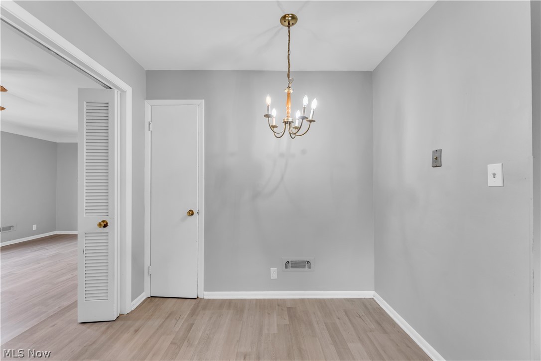 2915 Snow Road, Unit 2/UP Cleveland, OH 44134 - Photo 5 of 23 Dining area with light wood-finish flooring, light gray walls, and a brass-tone chandelier