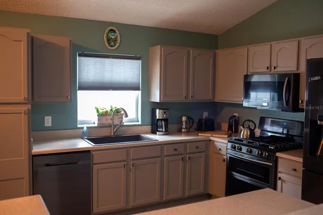 a kitchen with stainless steel appliances granite countertop a sink stove and microwave
