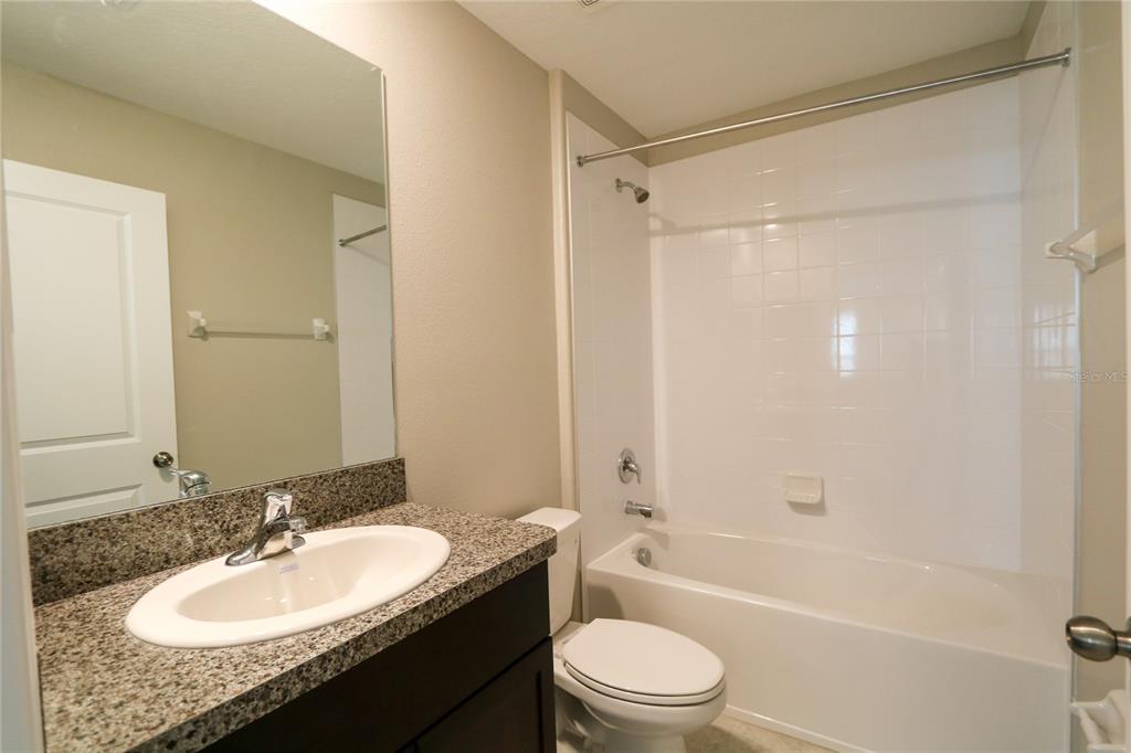 4714 Norman Oak Place Tampa, FL 33619 - Photo 17 of 32 a bathroom with a granite countertop sink toilet mirror and shower