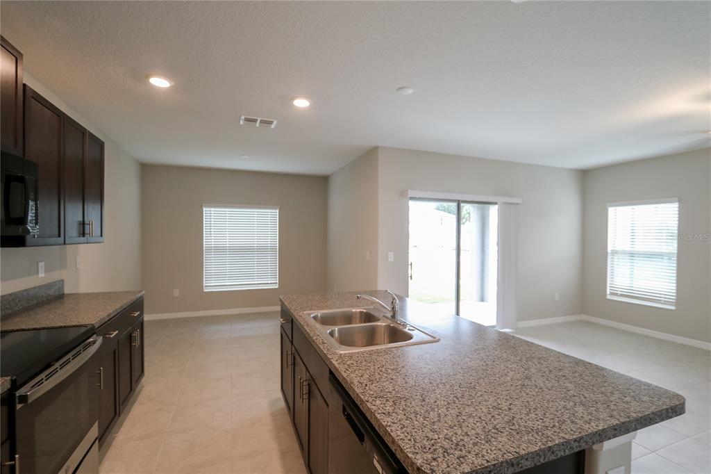 4714 Norman Oak Place Tampa, FL 33619 - Photo 6 of 32 a kitchen with stainless steel appliances granite countertop a sink a stove and a window