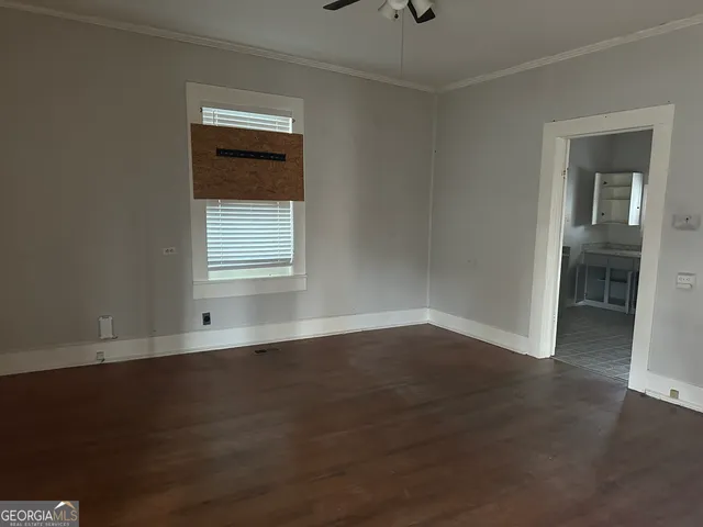 a view of an empty room with wooden floor and a window