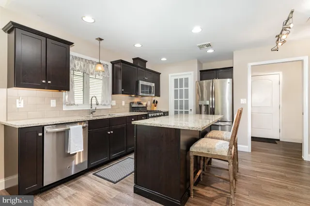 a kitchen with stainless steel appliances kitchen island a dining table chairs and a view of living room