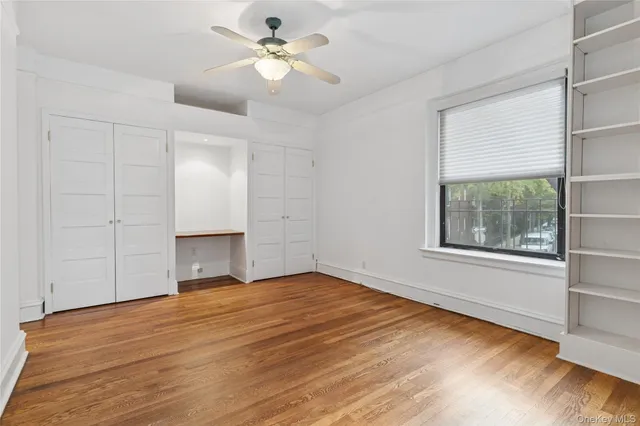 a view of empty room with wooden floor and fan