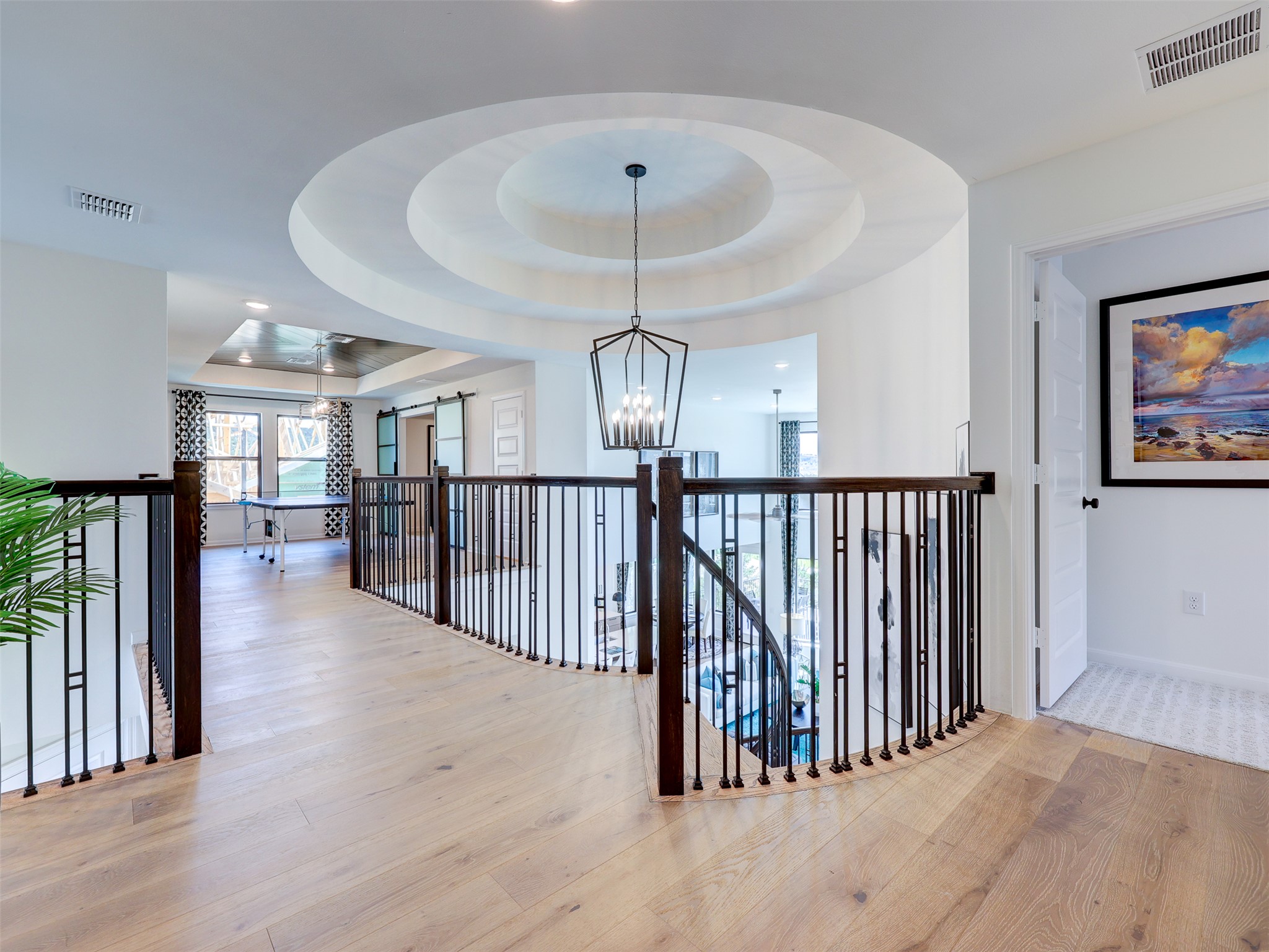 6220 Bower Well Road Austin, TX 78738 - Photo 20 of 28 A graceful staircase with wrought iron railings leads to a bright loft space featuring light hardwood flooring.