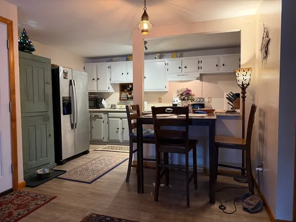 a kitchen with stainless steel appliances a dining table chairs refrigerator and sink