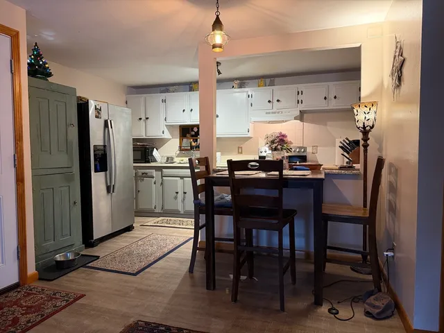 a kitchen with stainless steel appliances a dining table chairs refrigerator and sink