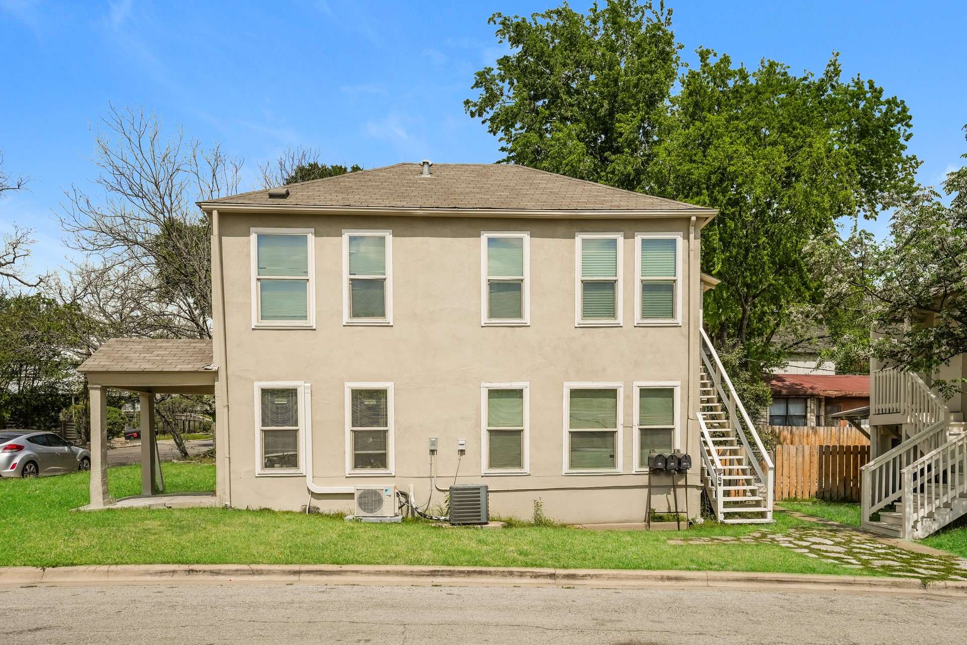 Rear view of property with stucco siding, a shingled roof, and a lawn
