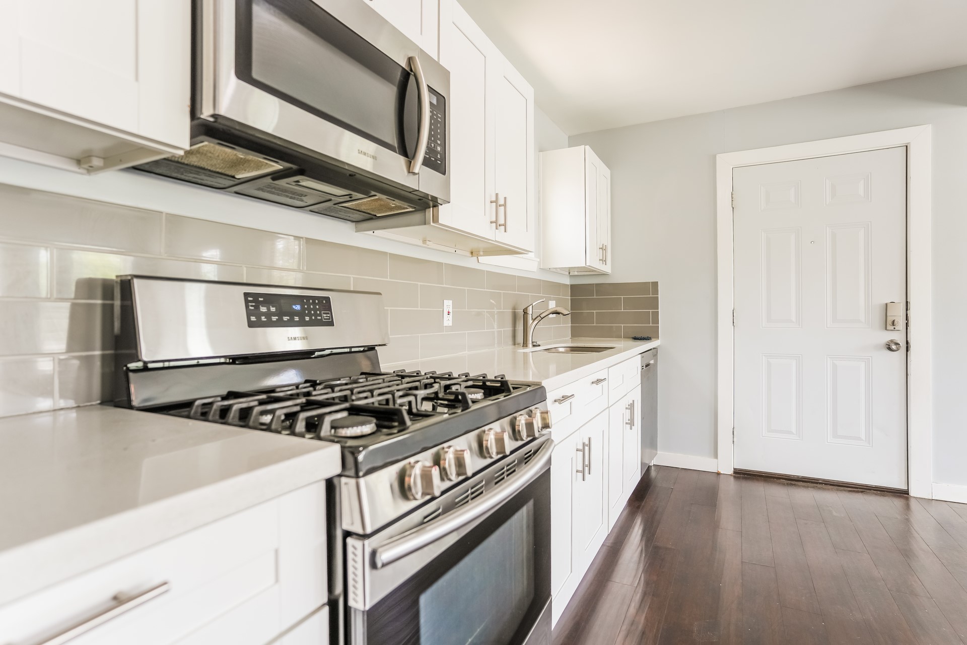 4801 Avenue H Austin, TX 78751 - Photo 10 of 16 Kitchen with stainless steel appliances, white cabinetry, tasteful backsplash, dark wood-type flooring, and light stone counters