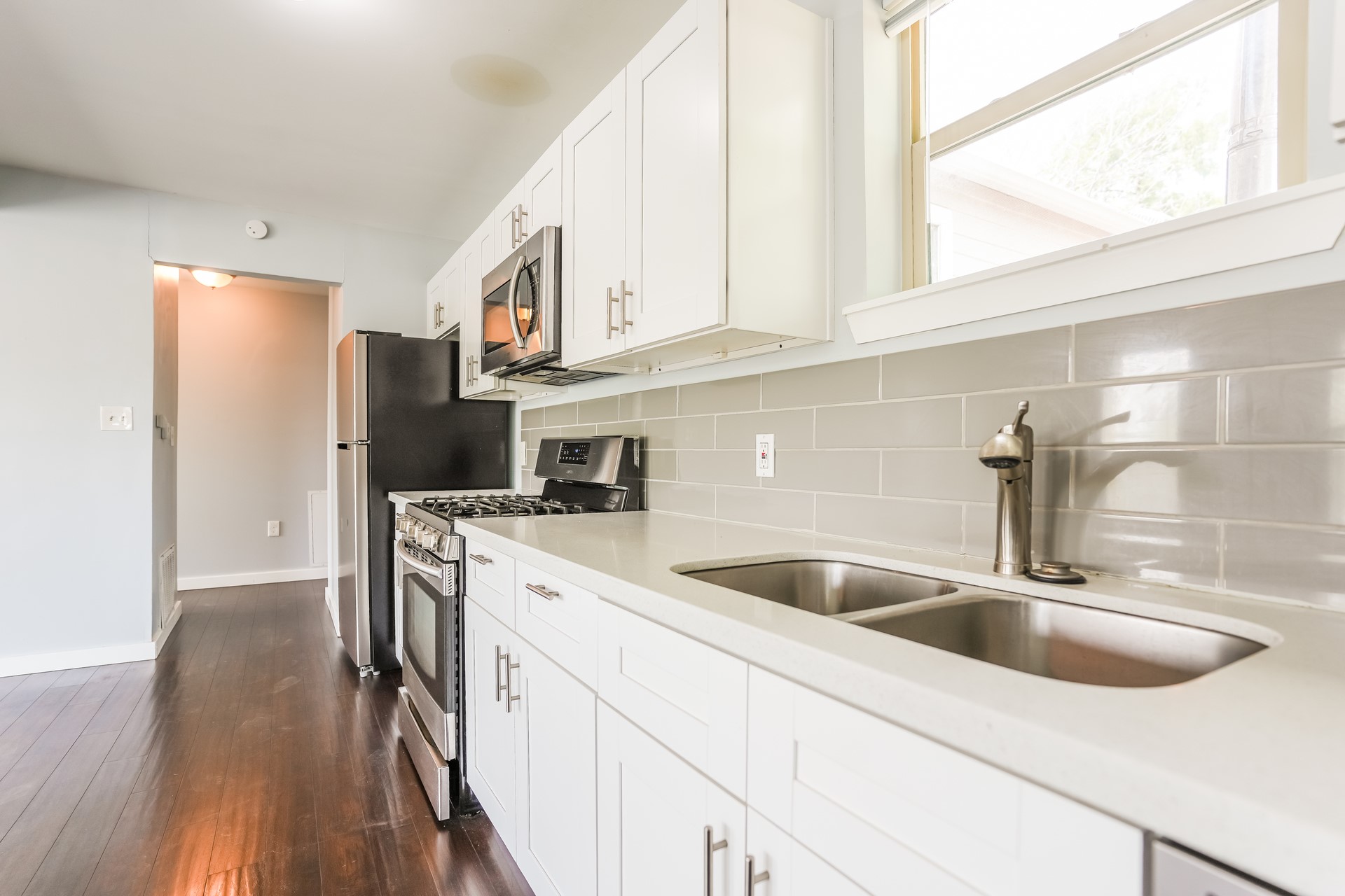 4801 Avenue H Austin, TX 78751 - Photo 15 of 16 Kitchen with stainless steel appliances, white cabinets, dark wood-style flooring, light stone counters, and tasteful backsplash