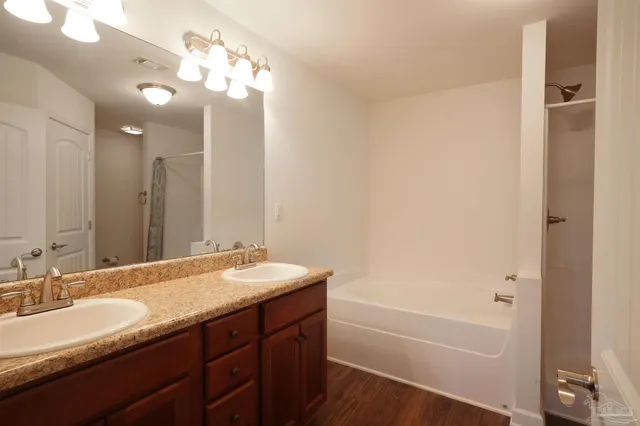a bathroom with a tub double sink and mirror