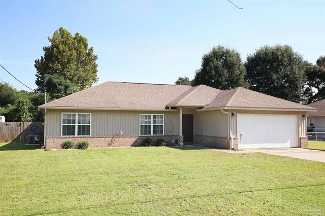 a front view of house with yard and trees in the background