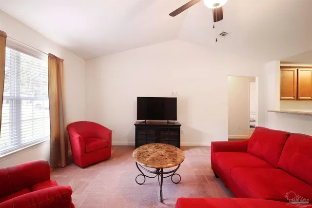 a living room with furniture a flat screen tv and a window