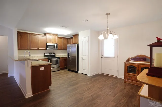 a kitchen with stainless steel appliances granite countertop a refrigerator a stove top oven a sink dishwasher and a refrigerator with wooden floor