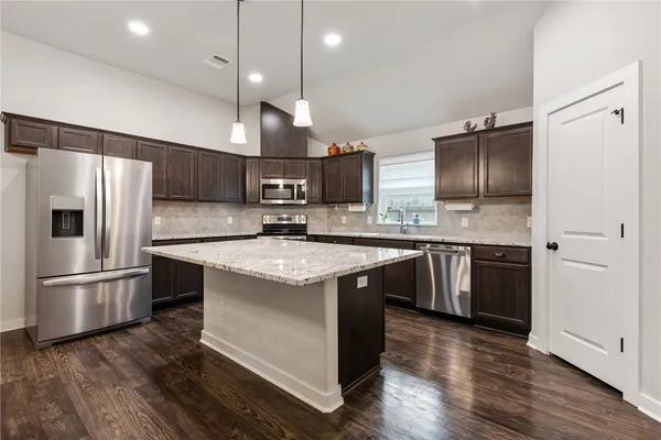 a kitchen with stainless steel appliances granite countertop a refrigerator a sink dishwasher a stove and a refrigerator