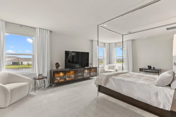 a bedroom with a bed and a flat tv screen on dresser