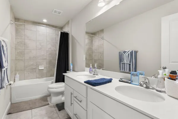 a bathroom with a double vanity sink toilet mirror and bathtub