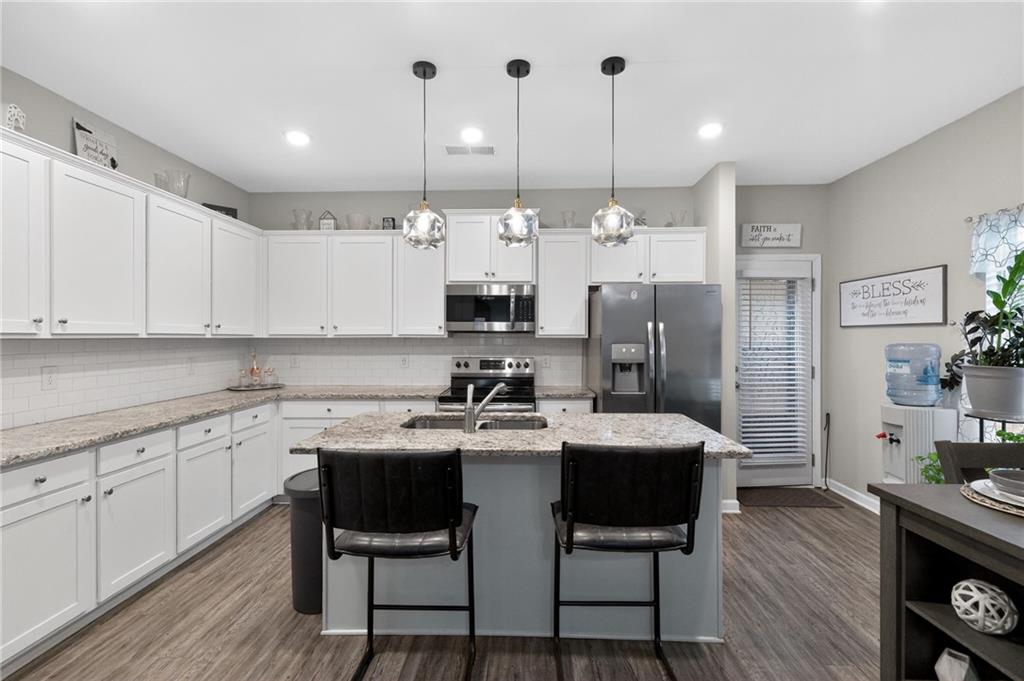 353 Daffodil Drive Temple, GA 30179 - Photo 11 of 30 a kitchen with stainless steel appliances kitchen island granite countertop a table chairs and a refrigerator