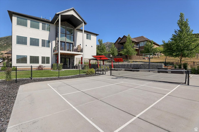 828 South Deer Road Tooele, UT 84074 - Photo 38 of 51 Concrete sports court with permanent net, bordered by dark gravel and a chain link fence