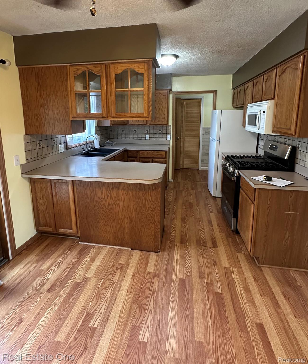 2430 Coolidge Road Barryton, MI 49305 - Photo 19 of 29 Kitchen featuring wood-finish flooring, wood cabinetry, built-in microwave, and a gas range